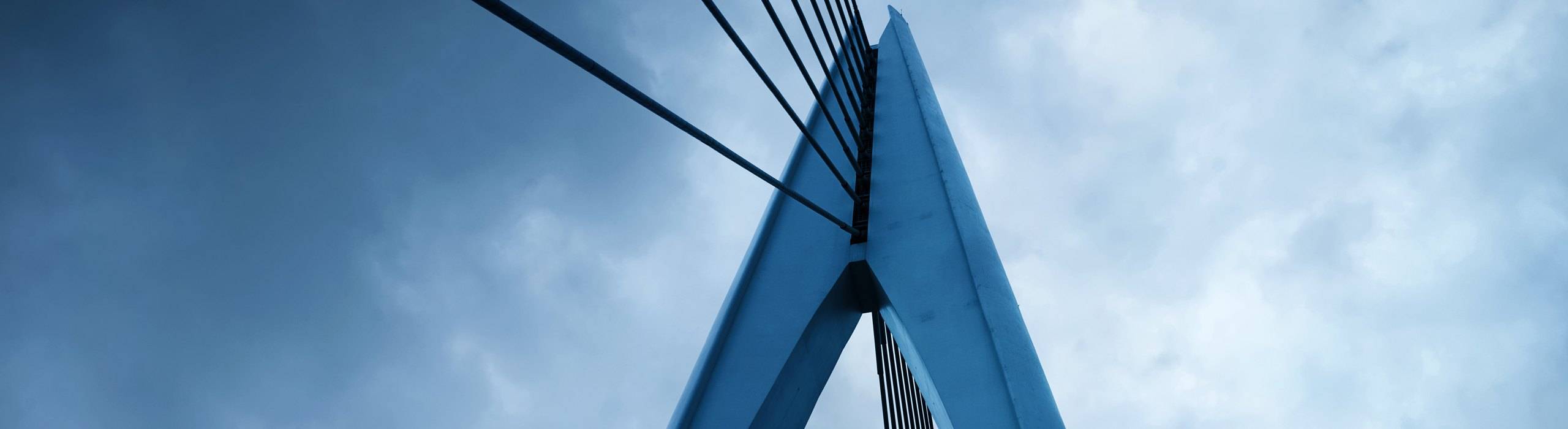 A blue cable-stayed bridge pylon against a stormy sky, for the direct lending maturity wall perspective.