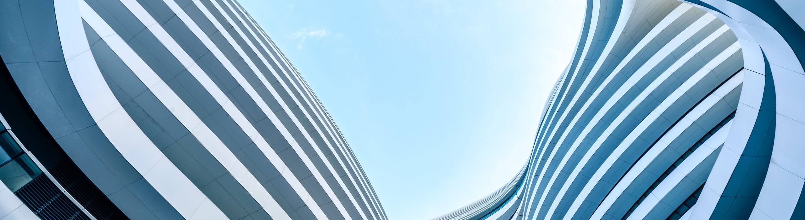 Two white, banded towers curving past each other under a pale sky